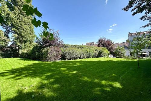 a large grassy field with trees and a hedge at The Retreat in Brussels
