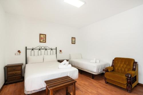 a bedroom with two beds and a chair at Hotel La Quinta de Santillán in Chinchón