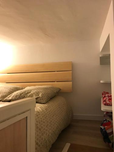 une chambre avec un lit avec une tête de lit en bois dans l'établissement Joli Cocon Paris 15ème, à Paris