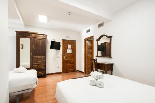 a hotel room with two beds and a desk at Hotel La Quinta de Santillán in Chinchón