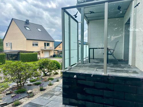 a house with a glass porch with a chair on it at Ferienwohnung Hochwaldblick 5 in Morbach