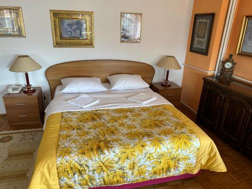 a bedroom with a large bed with a yellow blanket at Hondo Rooms & Apartments in Sarajevo