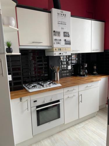 une cuisine avec des armoires blanches et un four à plaques de cuisson dans l'établissement Appartement hyper-centre à 200 m de la plage, à Royan