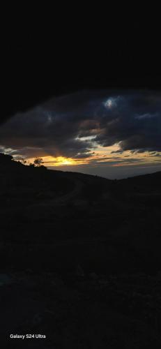 a sunset over a field with a cloudy sky at Dana historic village in Dana