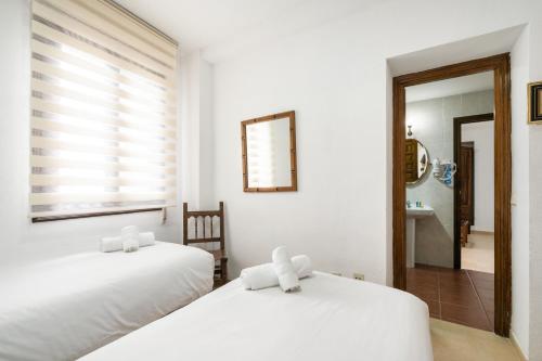 two white beds in a room with a mirror at Hotel La Quinta de Santillán in Chinchón