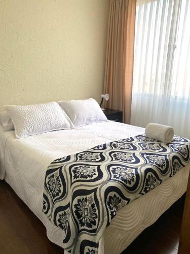 a bedroom with a bed with a black and white blanket at El Sosiego en Cochabamba in Cochabamba