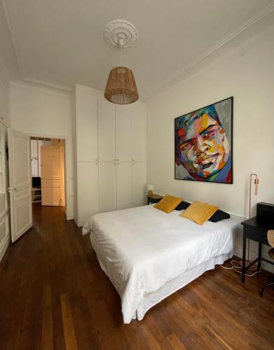 une chambre avec un lit blanc et un tableau au mur dans l'établissement Kak's apartments Paris, à Paris