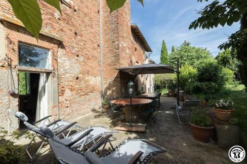 a patio with a table and chairs and an umbrella at Domaine d'en serres, 15th century castle in Saint-Marcel-Paulel