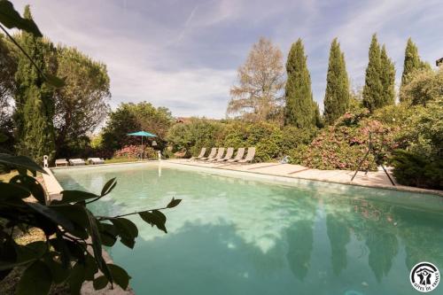 a swimming pool in a garden with trees at Domaine d'en serres, 15th century castle in Saint-Marcel-Paulel