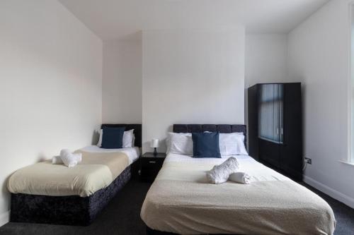 サンダーランドにある26 Riversdaleの白い壁の客室で、ベッド2台、青い枕が備わります。