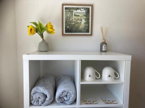a white shelf with towels and a vase on it at Henley Town Rooms in Henley on Thames