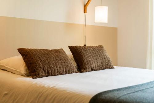 a bed with two brown pillows on top of it at Gite d'exception en pleine nature in Prémanon
