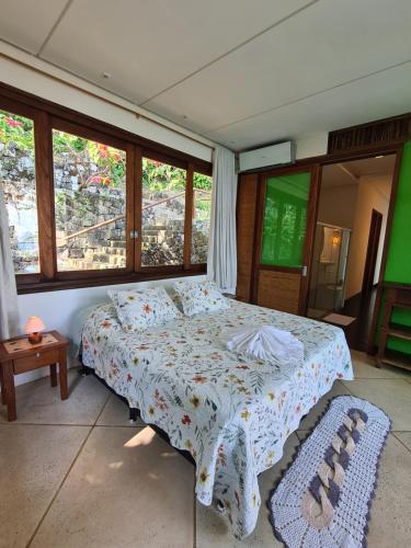 a bedroom with a bed with a comforter and windows at Paraíso Azul Retiro in Abraão