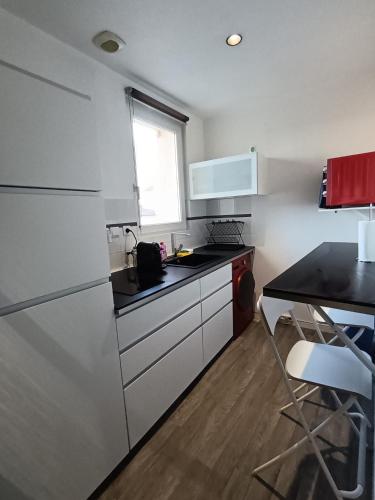 une cuisine avec des appareils blancs et un comptoir noir dans l'établissement T2 cosy en duplex, à Libourne