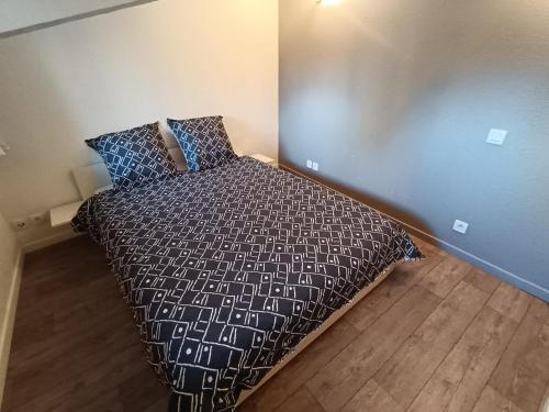 une chambre avec un lit avec une couette noire et blanche dans l'établissement T2 cosy en duplex, à Libourne