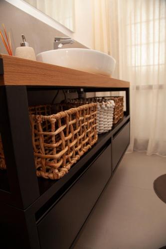 a bathroom with a vanity with a sink and baskets at Roussev Apartment - Coastal Gem - Anzio in Anzio