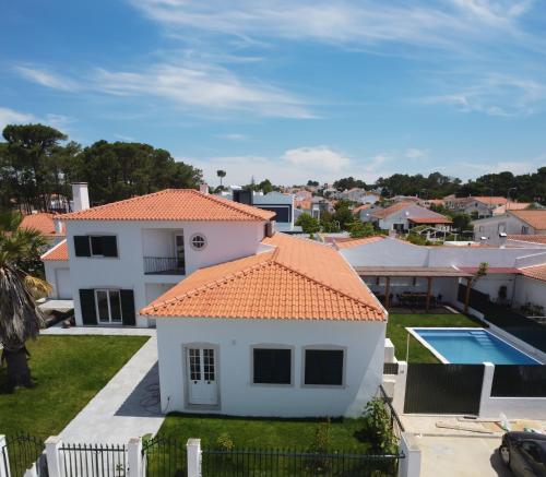 a white house with an orange roof and a pool at Casa do Mural - Heated Pool, Games Room & Beaches! in Sesimbra