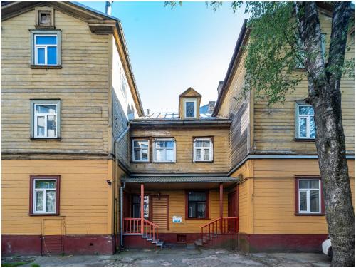 an old wooden house with a tree in front of it at Evena Travel Apartment in Rīga