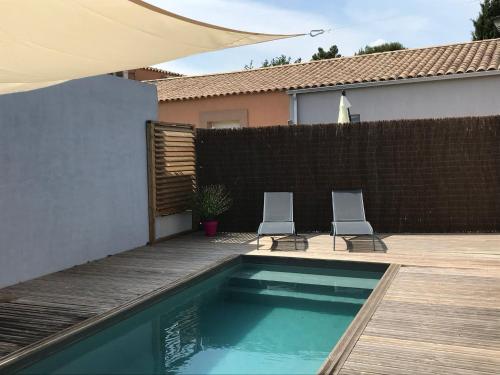 Deux chaises sont installées à côté de la piscine. dans l'établissement Maison avec piscine privative chauffée, à Sanary-sur-Mer