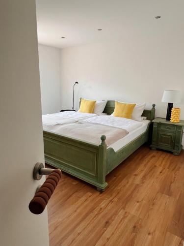 a green bed in a room with a wooden floor at Ferienwohnung am Rathaus in Wiesenbronn