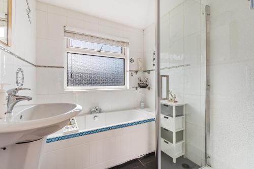 a white bathroom with a tub and a sink at The Pennines - Close to town beach and shops in Tenby