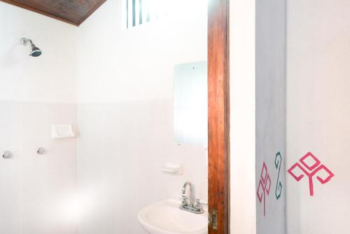 a white bathroom with a sink and a toilet at Hotel Taselotzin in Cuetzalán del Progreso