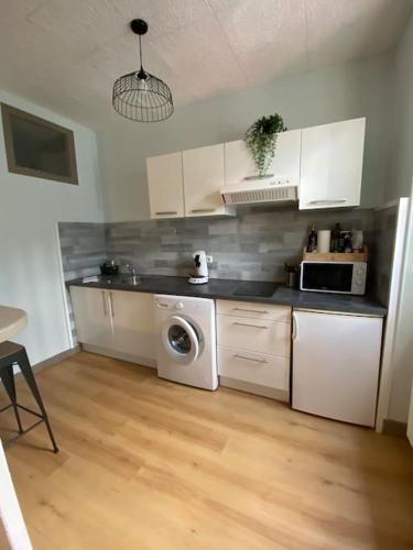 une cuisine avec un lave-linge et un micro-ondes dans l'établissement Le B2, parking privé, à Carcassonne