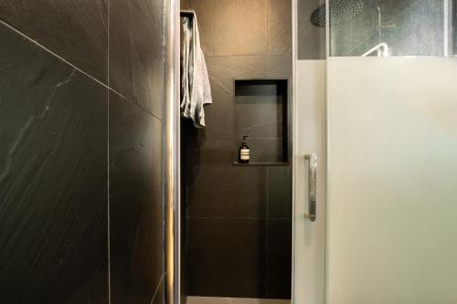 une salle de bain avec une douche avec une porte vitrée dans l'établissement Le Rousseau - proche du Louvre, à Paris