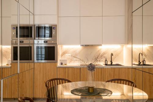 une cuisine avec une table avec des chaises et des armoires blanches dans l'établissement Le Rousseau - proche du Louvre, à Paris