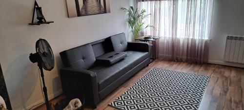 a black couch in a living room with a window at The Wee Bunker in Barassie
