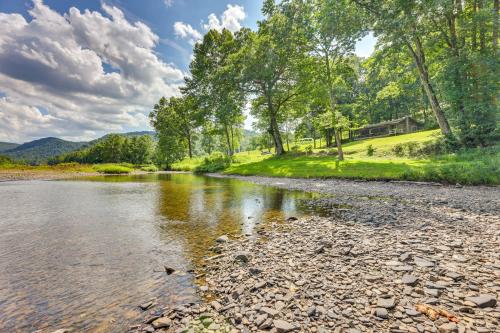 a river with trees and a house in the background at Charming Parsons Cabin with Grill on the Cheat River in Parsons