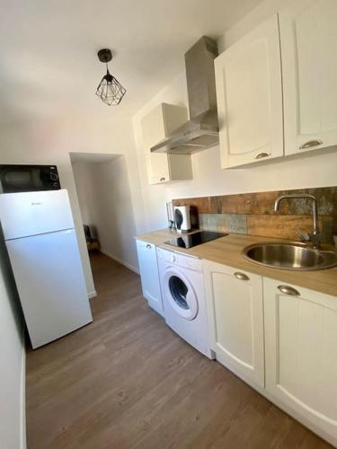 une cuisine avec des armoires blanches, un évier et un lave-vaisselle dans l'établissement Le B3, parking privé, à Carcassonne