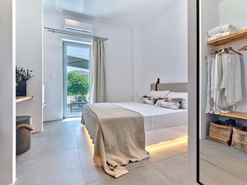 a white bedroom with a bed and a sliding glass door at Blue Mare Villas in Naousa