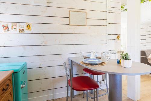 a small table with two red chairs and a white wall at La parenthèse chambonnaise - chalet cosy, WIFI in Le Chambon-sur-Lignon
