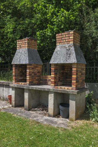 a brick barbecue grill in the grass in a yard at La parenthèse chambonnaise - chalet cosy, WIFI in Le Chambon-sur-Lignon