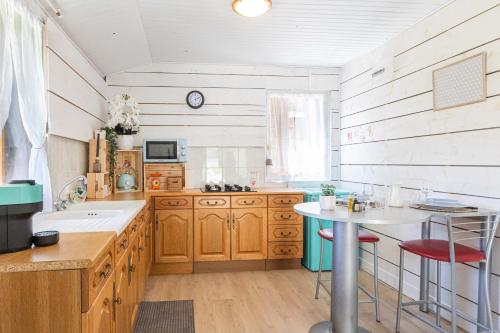 a kitchen with wooden cabinets and a table in it at La parenthèse chambonnaise - chalet cosy, WIFI in Le Chambon-sur-Lignon
