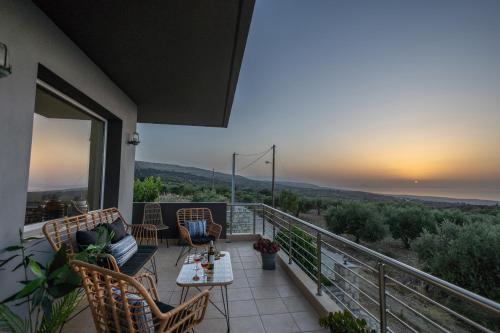 a balcony with chairs and a table and a sunset at Country House Crete in Amnátos