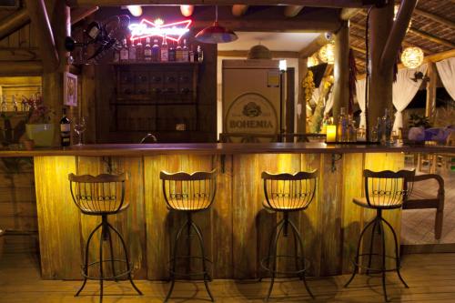 a bar with three bar stools in a room at Pousada de Charme Emirados in Ilhabela