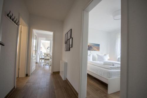 ein weißes Schlafzimmer mit einem Bett und einem Flur in der Unterkunft Cuxhavener Straße 5/3 in Cuxhaven