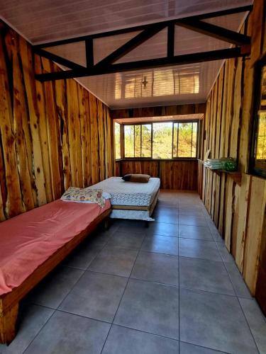 a bedroom with two beds in a wooden cabin at SL Montaña Tranquila in Esperanza
