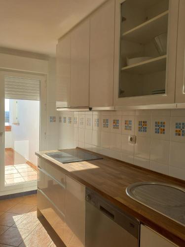 アヤモンテにあるMirador del Guadianaの白いキャビネットと木製のカウンタートップを備えたキッチン