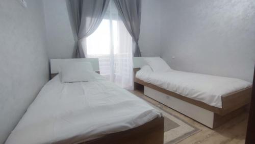 a small room with two beds and a window at Palm Beach Saidia Maroc in Saidia 