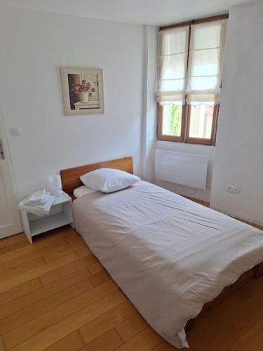 une chambre avec un lit blanc et une fenêtre dans l'établissement Ruelle maison ancienne, à Saint-Romain