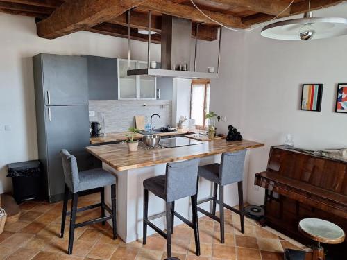 een keuken met een groot houten eiland met barkrukken bij Ruelle maison ancienne in Saint-Romain