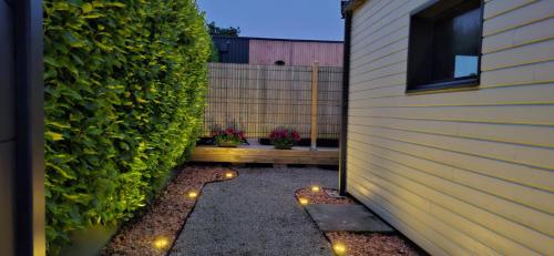 un jardin avec un banc et des lumières à côté d'un bâtiment dans l'établissement Location Finistère Jaccuzi privé, à Plougourvest