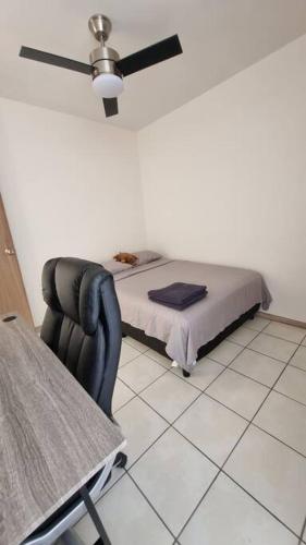 a bedroom with a bed and a chair with a fan at Excelente lugar para descansar in Emiliano Zapata