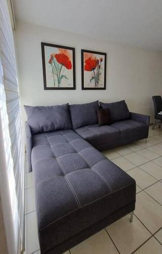 a blue couch in a living room with two pictures at Excelente lugar para descansar in Emiliano Zapata