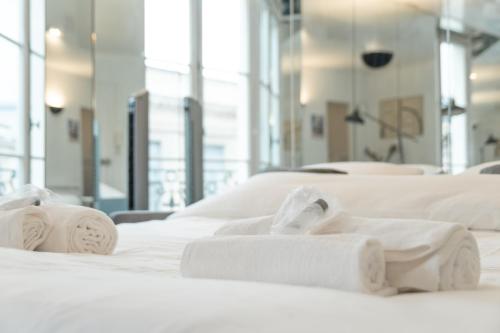 un groupe de serviettes blanches posées sur un lit dans l'établissement Studio at Jardin du Luxembourg, à Paris