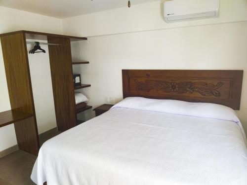 a bedroom with a white bed with a wooden headboard at Departamento Concha de Mar in Puerto Vallarta