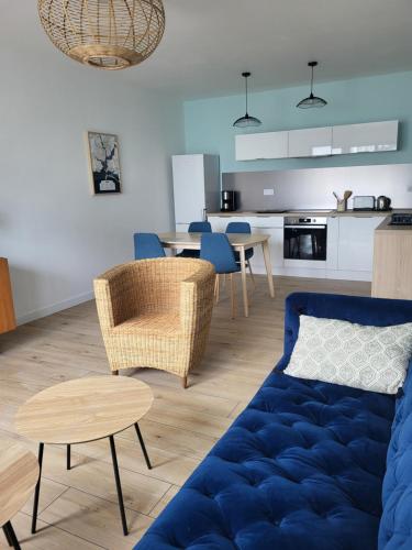 un salon avec un canapé bleu et une cuisine dans l'établissement Plein pied de la petite mer, à Riantec